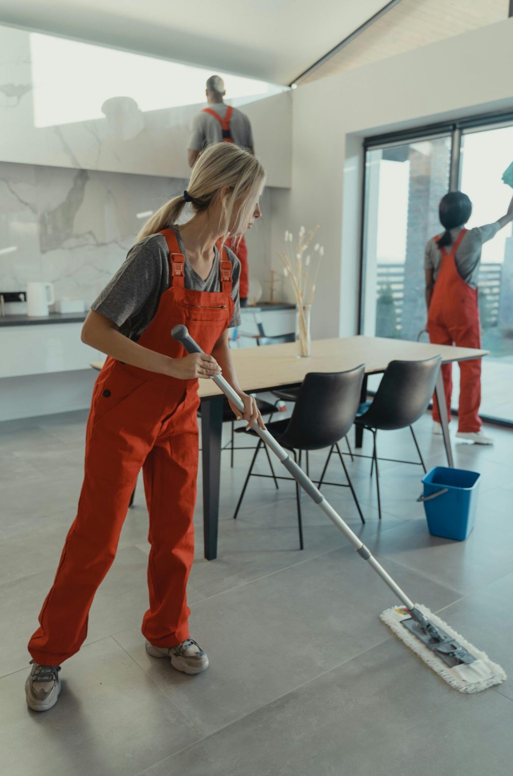pexels-photo-6197116-6197116 Cleaning team in red overalls mopping and sanitizing a modern home interior.